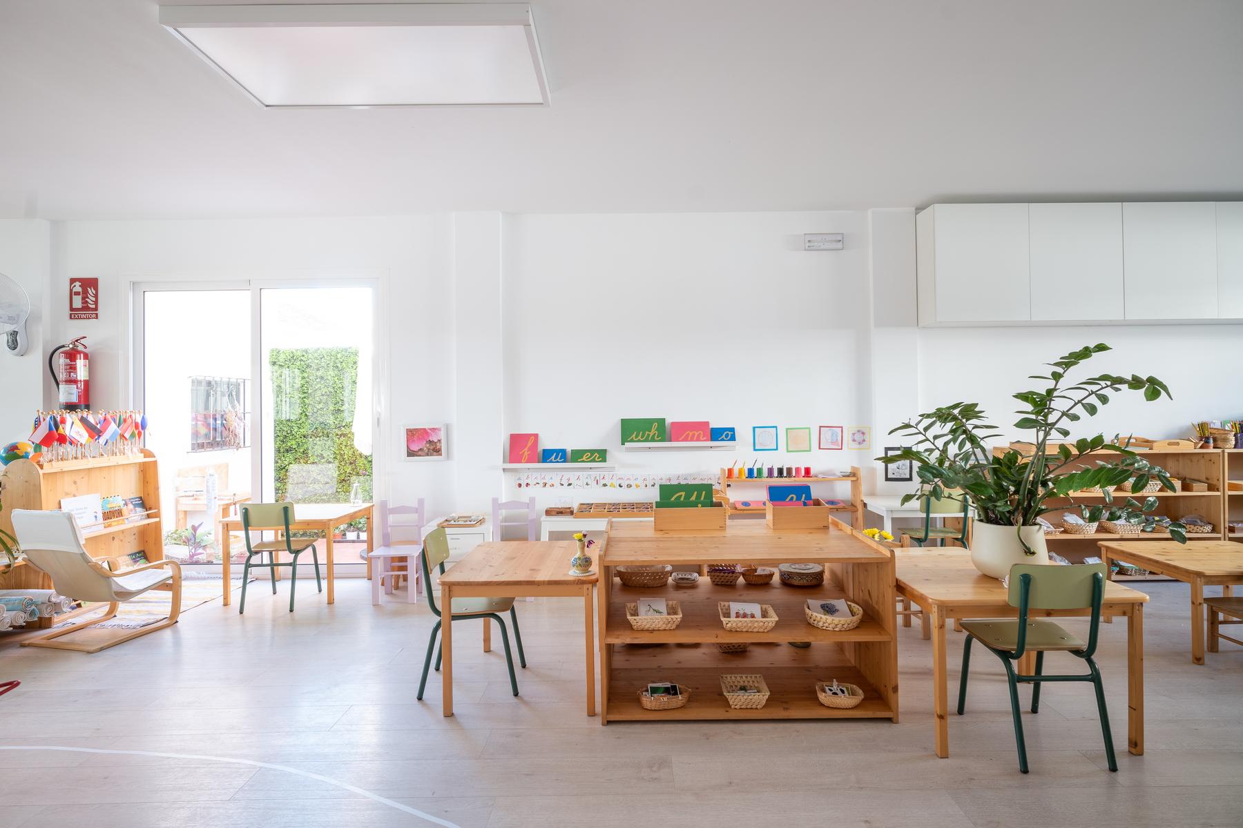 A bright Early Childhood classroom at Casa del Mar Montessori, with low wooden shelves of materials, child-sized tables and plants