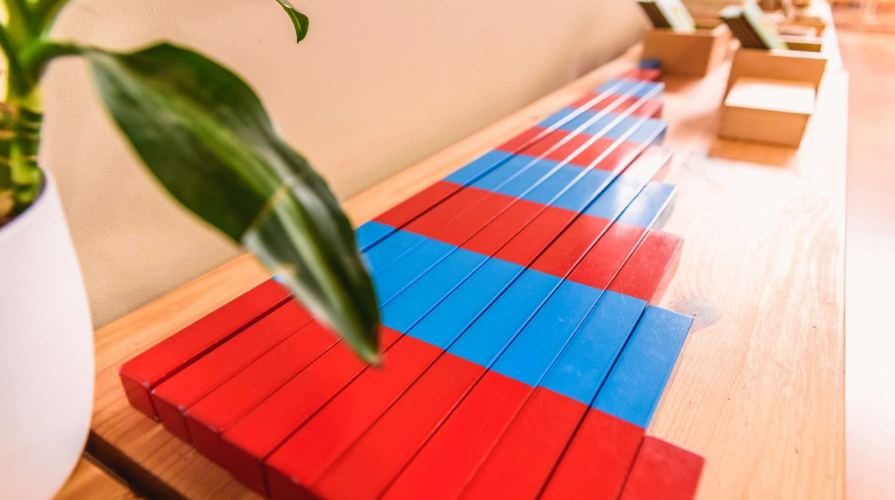 Red and blue Montessori number rods laid out on a wooden table